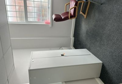 Small office or consulting room with a red leather armchair and white storage cabinet.