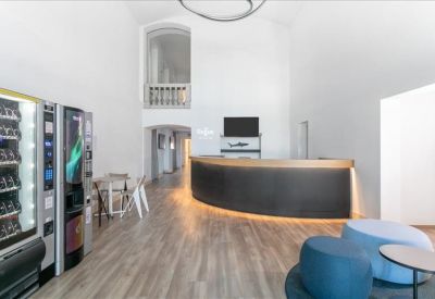 Minimalist reception area with a curved black desk, vending machines, and high ceilings.
