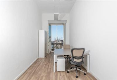 Narrow private office with a single desk, ergonomic chair, and wood-finish flooring.