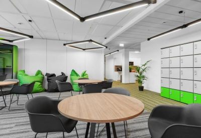 Breakout area with wooden tables, black chairs, and vibrant green beanbags.