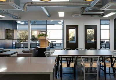 Contemporary breakout area with a large black dining table and views into a lounge.