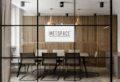 Professional meeting room seen through a black-framed glass wall with wood paneling.