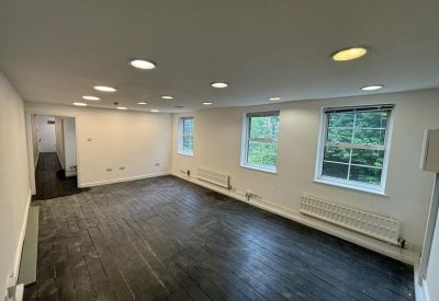 Spacious open-plan office area with dark wood flooring and recessed ceiling lights.