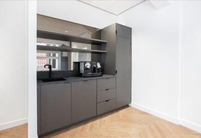 Sleek dark grey kitchen area with integrated espresso machine and wooden flooring.