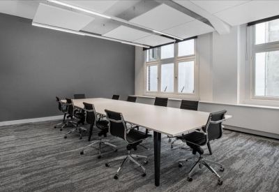 Long boardroom table with black mesh chairs and acoustic ceiling panels.