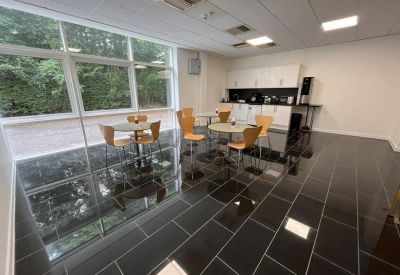Communal kitchen and breakout area with glossy black tiling and wooden chairs.