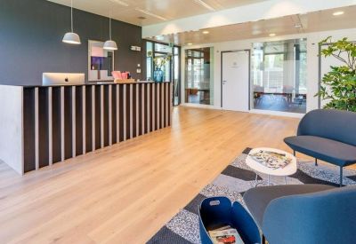Modern reception area with a wood-slatted desk and a blue sofa seating area.