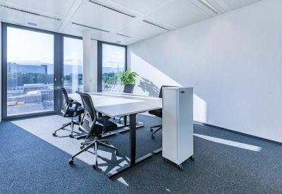 Bright private office featuring white desks, ergonomic black chairs, and large windows.