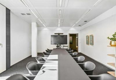 Sleek conference room with a long table, black chairs, and a large wall-mounted monitor.