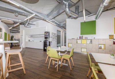 Casual breakout area with cafe-style seating and vibrant green wall decor.