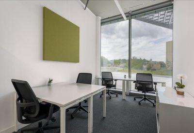 Private office with four desks and large windows overlooking green space.