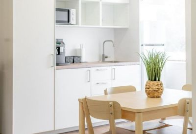 Modern white kitchenette and wooden dining table with chairs.