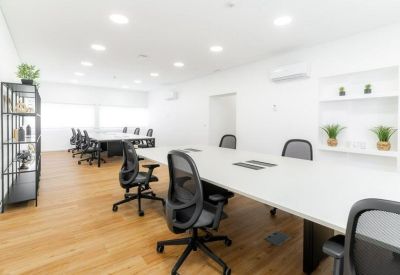 Spacious meeting area with long white tables and ergonomic black chairs.
