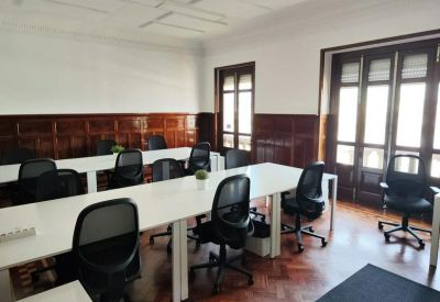 Bright open-plan workspace with white desks, black ergonomic chairs, and wood-paneled walls.
