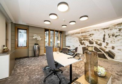 Private office suite with a minimalist white desk, grey seating, and a large artistic wall map.