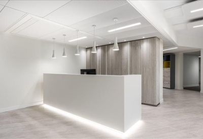 Minimalist reception desk with a backlit base and modern pendant lighting.