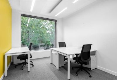 Private office featuring white desks and a vibrant yellow accent wall.