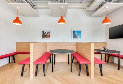 Communal breakout area featuring wooden booths with red bench seating and orange pendant lights.
