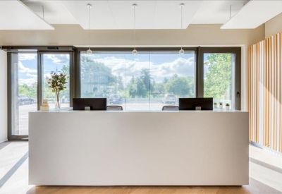 Minimalist white reception desk positioned in front of a large window with greenery views.