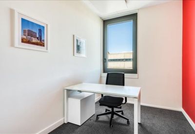 Private office suite with a white desk, ergonomic chair, and framed wall art.
