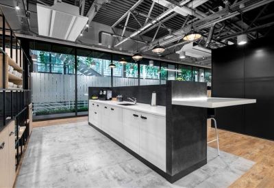 Industrial-style kitchen area with a white island, black cabinetry, and exposed ceiling.
