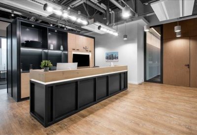 Modern reception area with a black and wood desk under industrial lighting.
