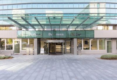 Modern glass building entrance with a revolving door and canopy.