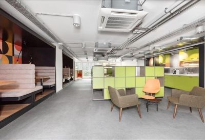 Spacious communal breakout area with green shelving, lounge chairs, and booth seating.