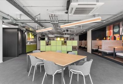 Casual meeting area featuring a wooden table, grey chairs, and colorful wall graphics.