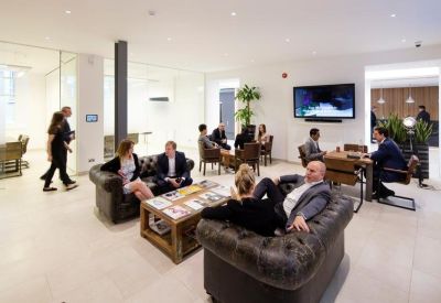 Modern breakout lounge featuring plush leather sofas, a media screen, and contemporary lighting.