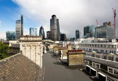 Rooftop view looking over traditional chimneys toward the modern London city skyline.