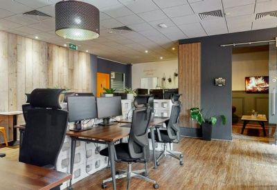 Modern open-plan office with timber desks and ergonomic black chairs.