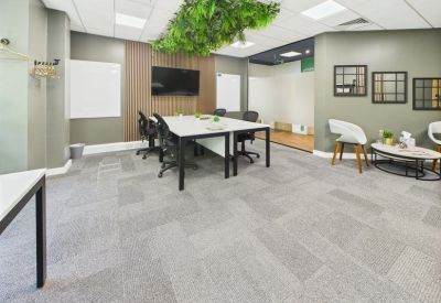 Professional meeting area with a long white table and overhead greenery installation.