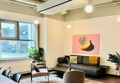 Modern lounge area with a dark sofa, pink banana artwork, and designer pendant lights.