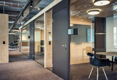 Modern office corridor with glass partitions and seating.