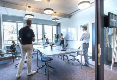 Bright meeting room with large windows and several people.