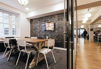 Meeting room with a wooden table, mixed seating, and a dark brick feature wall.