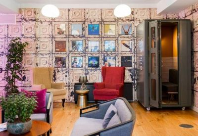Eclectic lounge area with vibrant wallpaper, colorful armchairs, and a vintage phone booth.