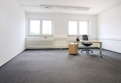 Private office suite with gray carpeting, two large windows, and a minimalist desk setup.