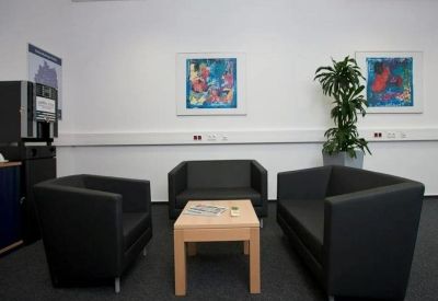 Casual breakout area with black leather armchairs and colorful abstract wall art.