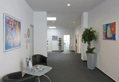 Spacious reception hallway with modern art, seating area, and potted plants.