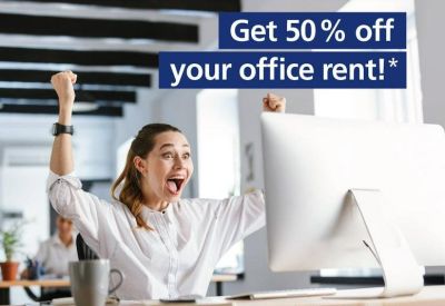 Cheerful woman celebrating at a bright workstation with a large monitor.