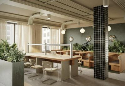 Coworking area with long wooden tables, ergonomic chairs, and lush green plants.