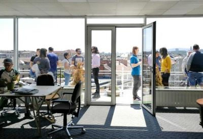 Indoor breakout area with a large glass door leading to a balcony with city views.
