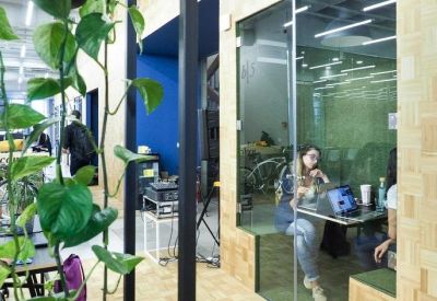 Glass-enclosed phone booth or small meeting pod with wooden walls and indoor plants.