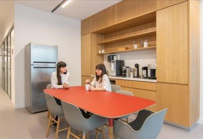 Staff kitchen and breakout area with a red table and wooden cabinetry.