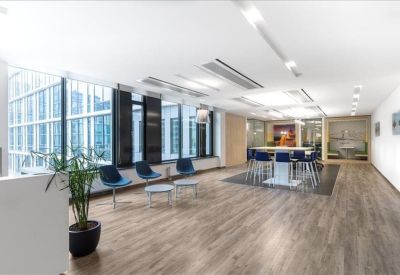 Modern reception lounge with polished wood floors and blue seating by large windows.