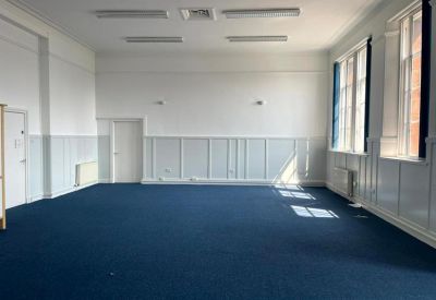Spacious open-plan office suite with blue carpeting, white walls, and large windows.