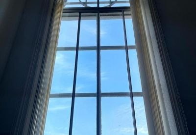 Close-up of a tall, classic sash window showing a bright blue sky.