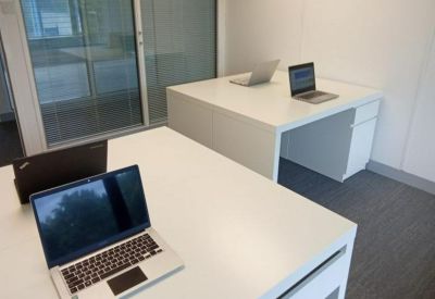 Private office with white corner desk and frosted glass partition.